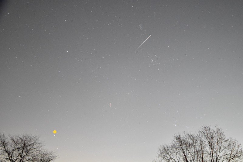 An upward-moving meteor between the Pleiades (above the meteor) and the Hyades (below the meteor)