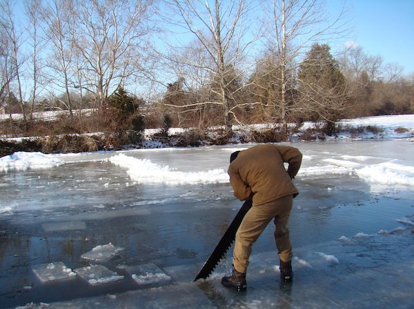 Man cutting ice with a saw