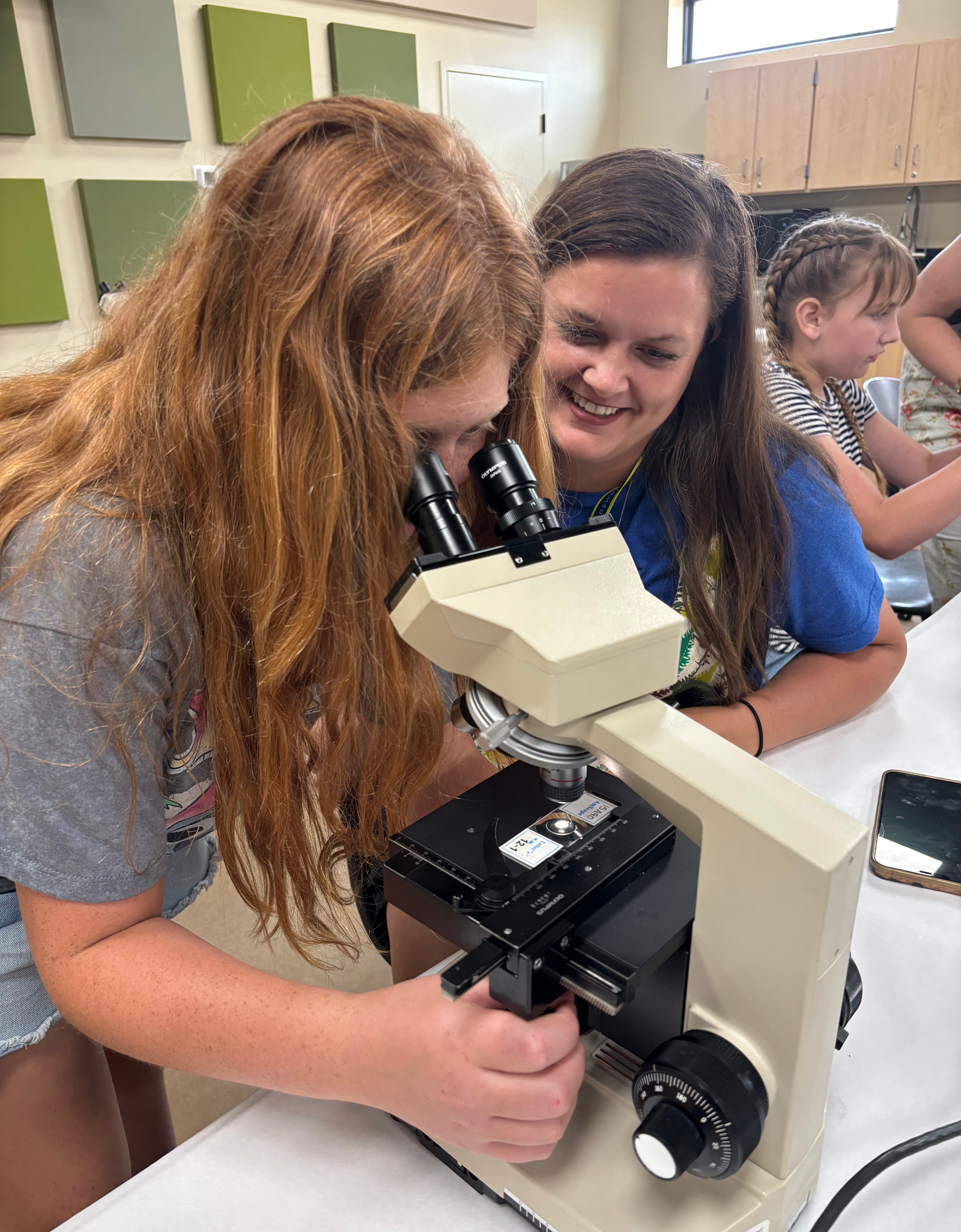Girl and mom by a microscope.