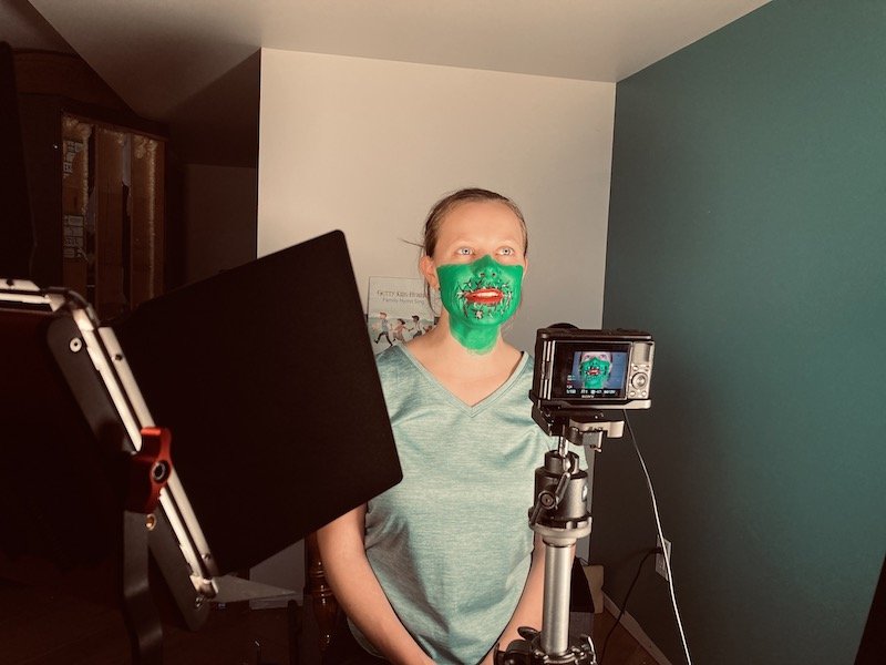 Avery filming with green-painted face.