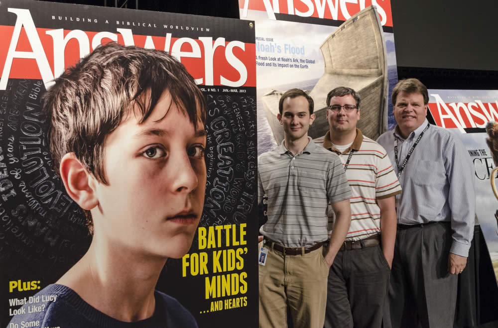 Chris, Dan, and Dale standing to the side of the cover illustration that won first place