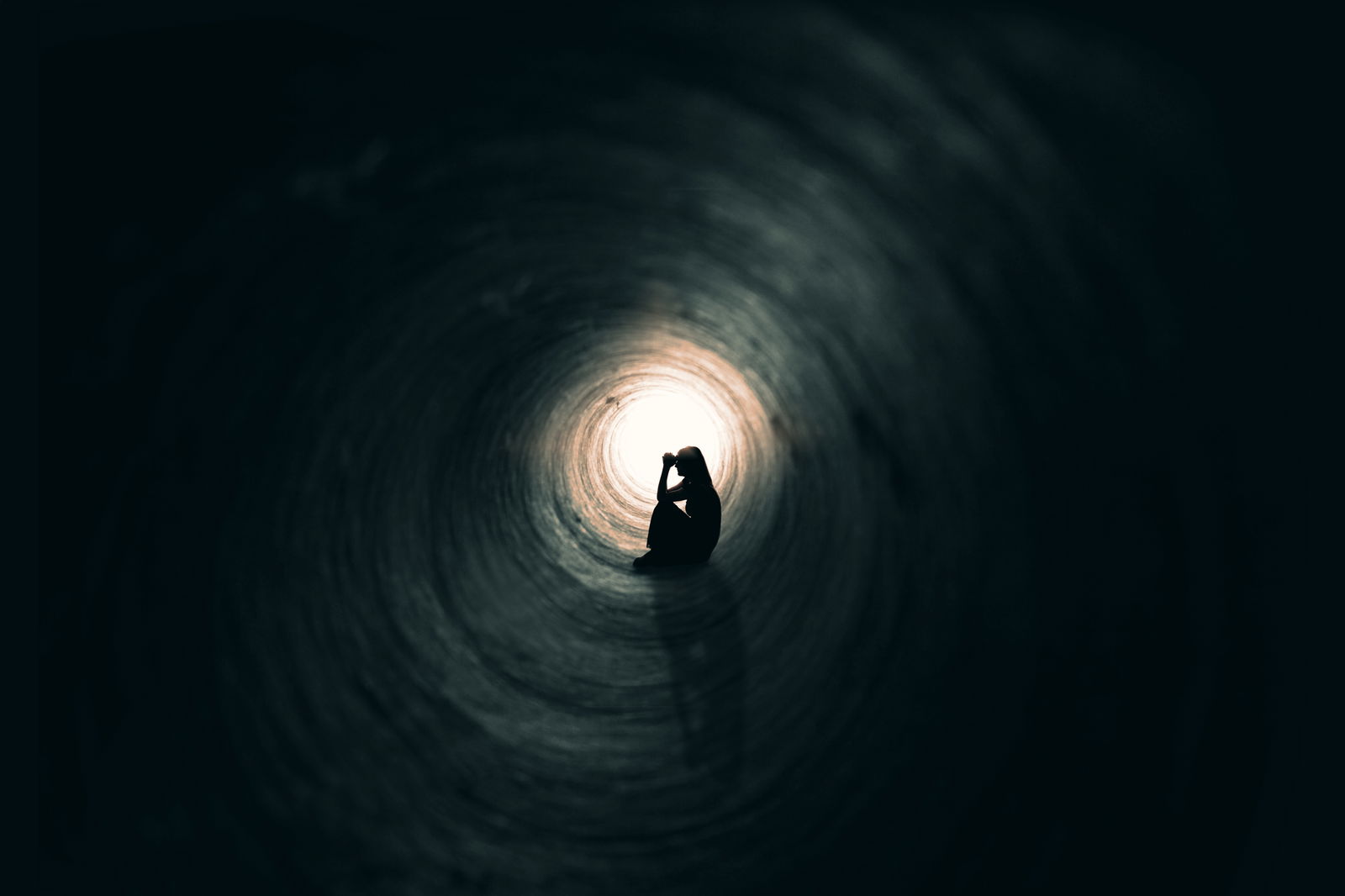 woman praying in a dark tunnel