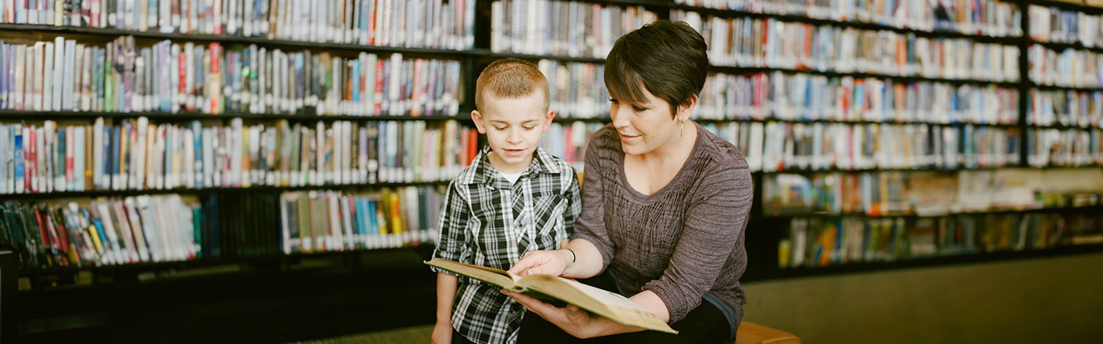 Teacher pointing at book with student