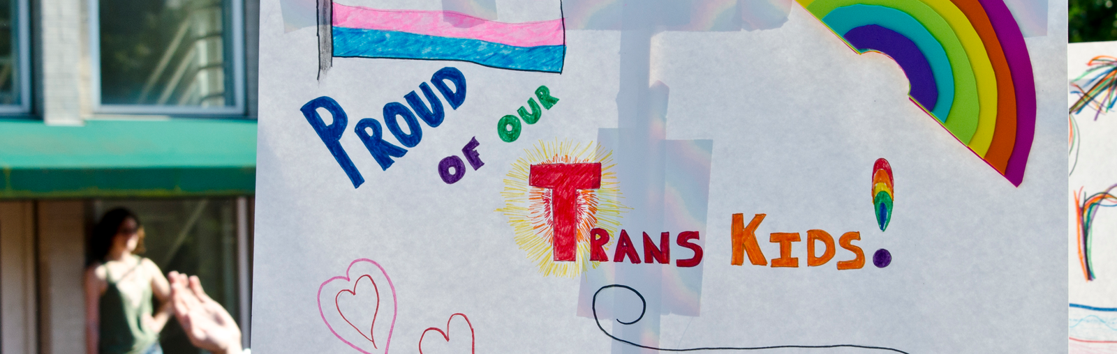 a sign that says "proud of our trans kids"