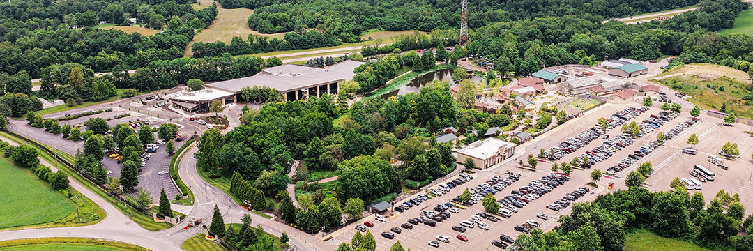 Aerial view of the Creation Museum campus surrounded by trees, gardens, and full parking lots